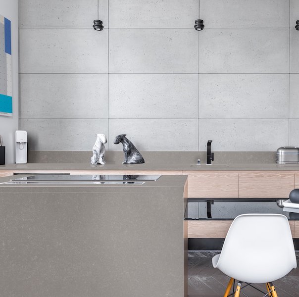 HanStone Quartz Uptown Grey modern grey quartz countertop surface available in both polished and leather finishes modern kitchen scent with quartz countertops and waterfall edge white molded eames chair concrete wall wood architectural accents